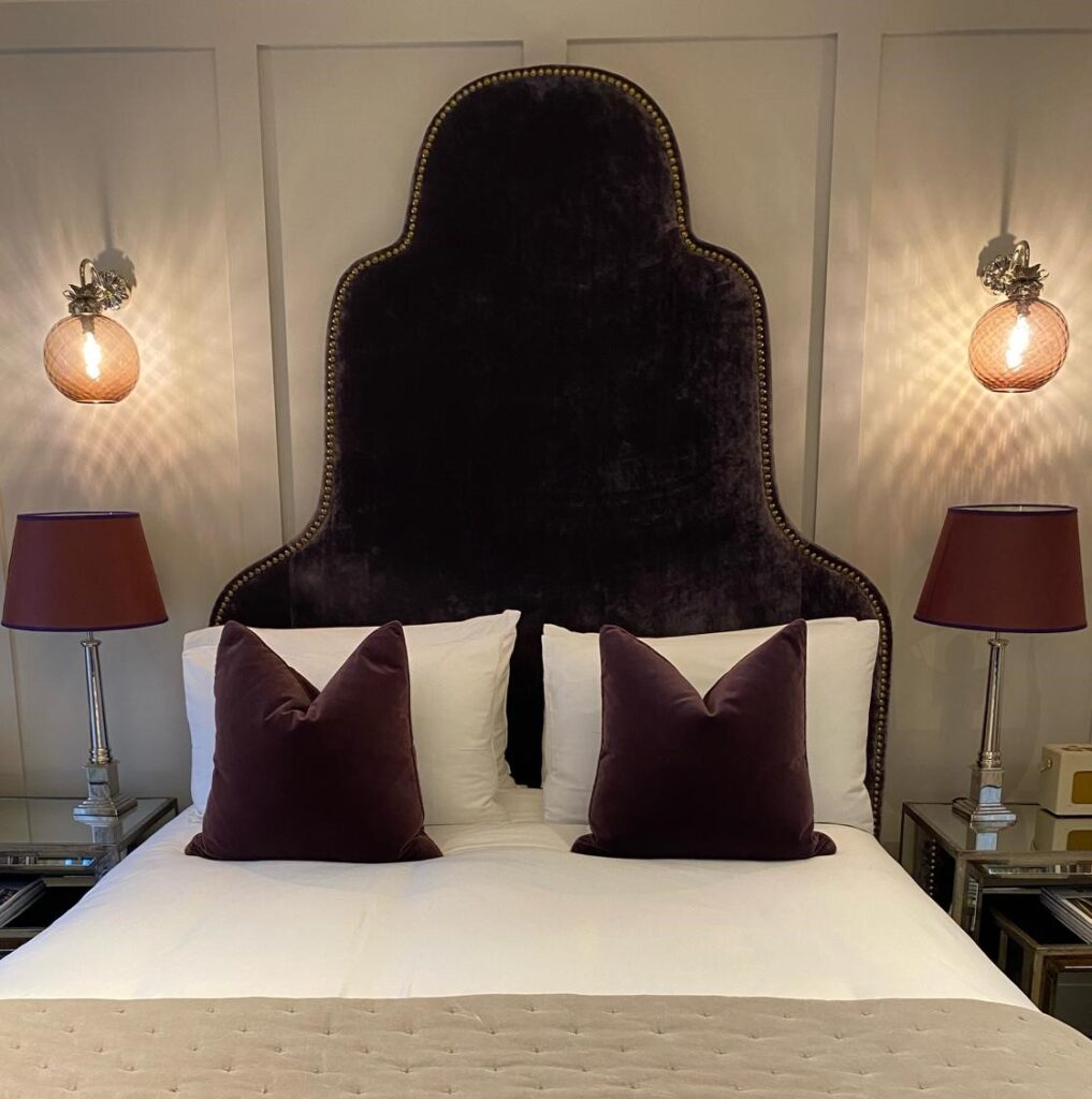 A close-up view of a bedroom headboard against wooden paneling in the rooms at Manor House Lindley.