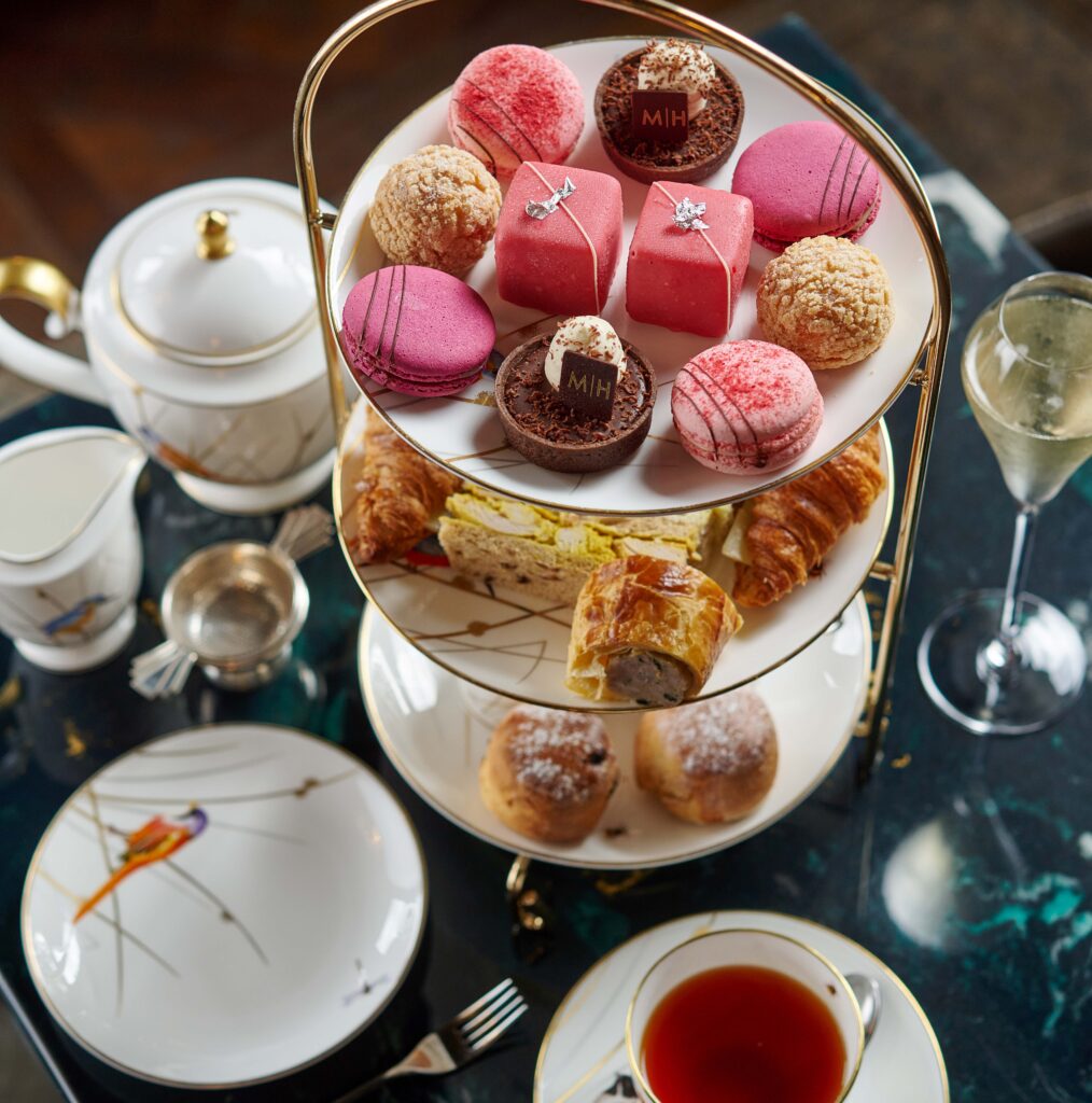 A close-up picture of Valentine's Afternoon Tea with sweet treats on a three-tier stand, teapot, and glass of fizz.